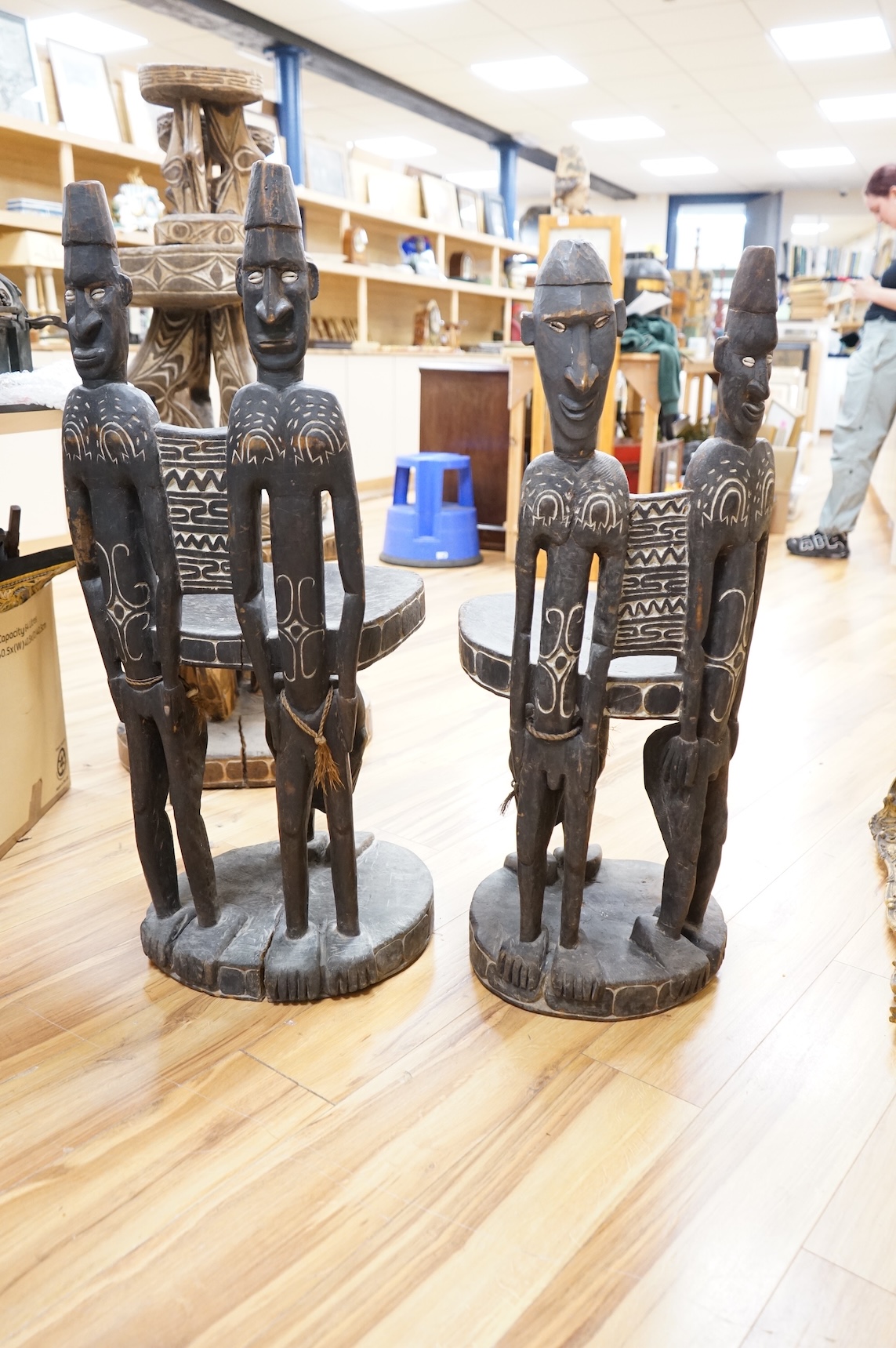 Papua New Guinea Sepik River, a near pair of ‘ceremonial’ figural chairs, each carved from a single section of a tree trunk with integral male and female backs and an castor figure front support with cowrie shell eyes. H